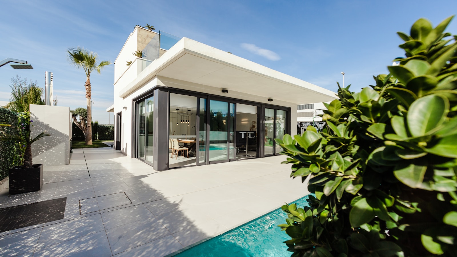 Bright modern Orange County home with palm tree, pool and sunlit patio — coastal California curb appeal